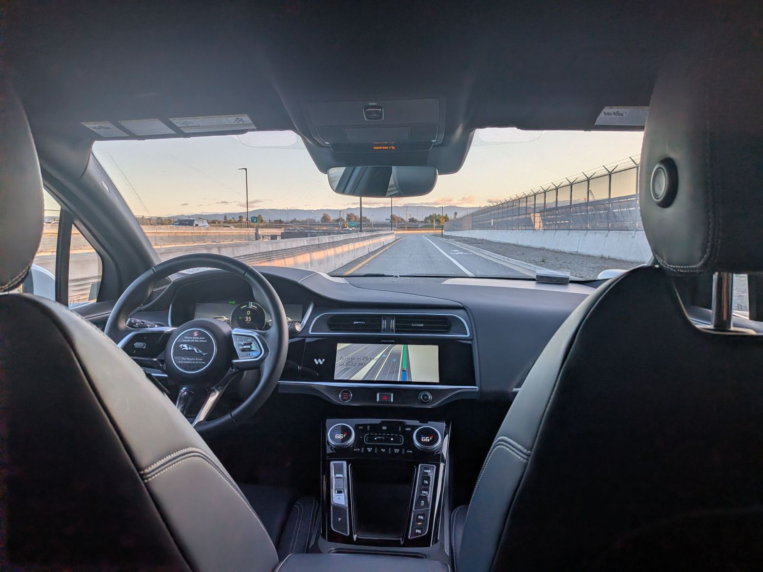 view from the rear passenger seat of a Waymo driverless vehicle looking down a road